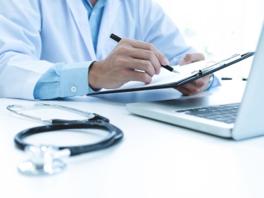 doctor-working-with-laptop-computer-writing-paperwork-hospital-background_1